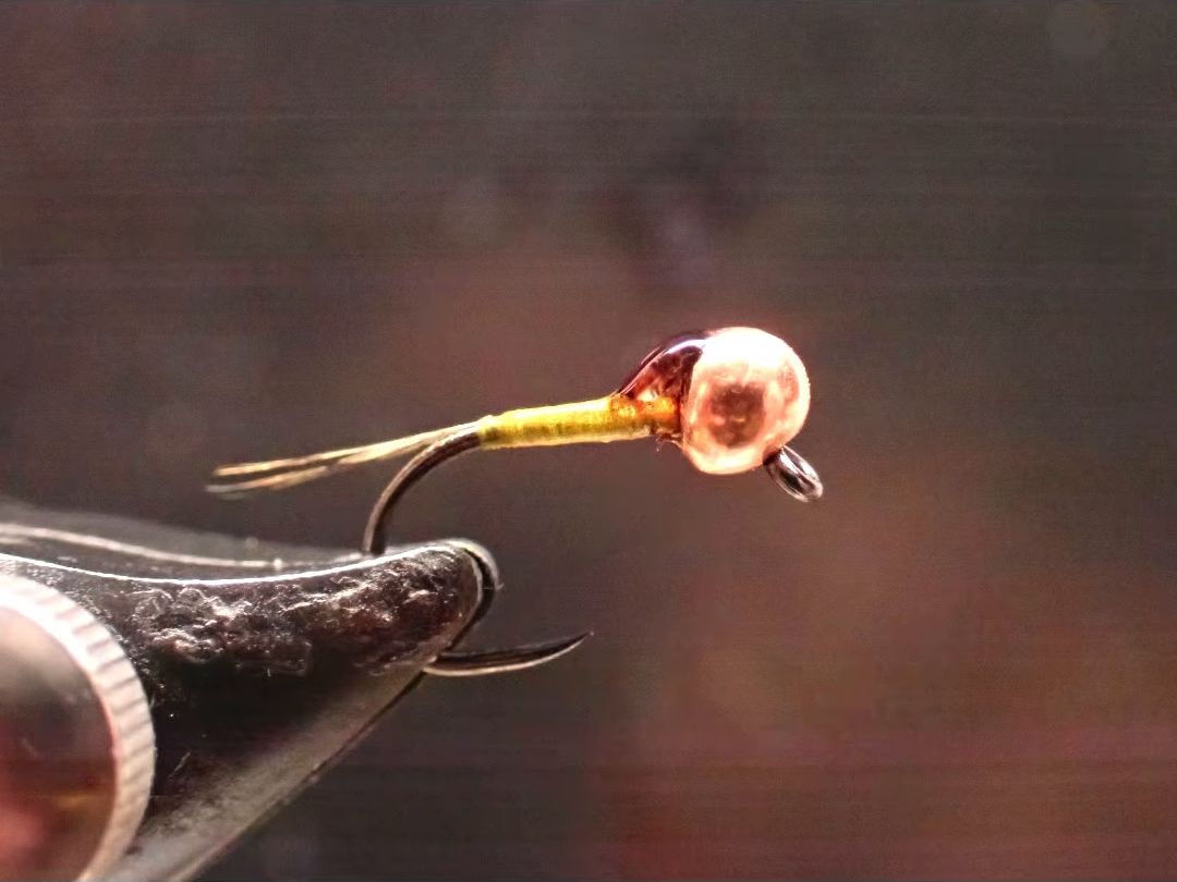 A finished copper beadhead nymph in the vise