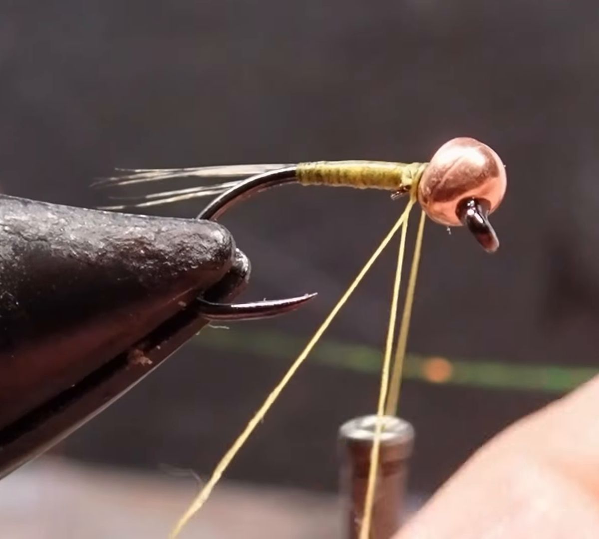 A copper-bead nymph being tied in a fly-tying vise