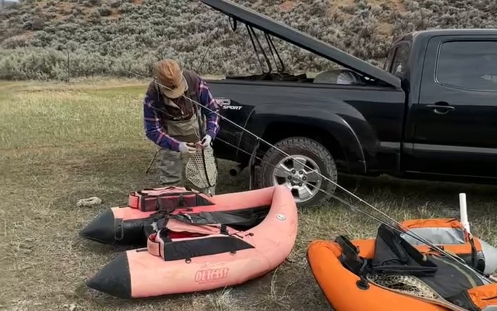 An angler rigging beside two float tubes and a truck